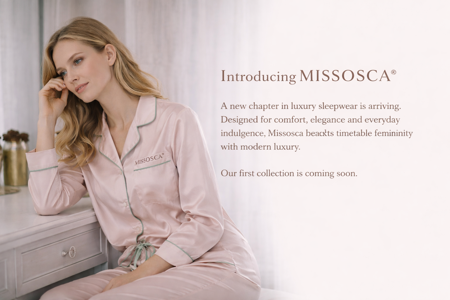 Woman at beauty vanity wearing Missosca® luxury satin pajamas with embroidered logo, introducing the upcoming Missosca sleepwear collection
